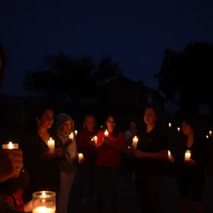 Community members holding candles in a vigil for a shooting victim in San Antonio.